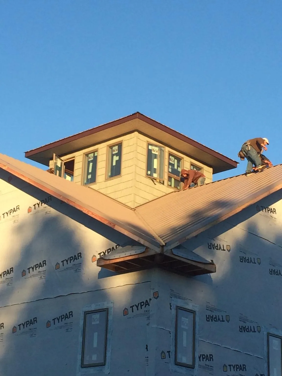 Roofers working around a rooftop cupola on a new metal roof at sunset — Roof Waterproofing in Gettysburg by Roofing Brothers
